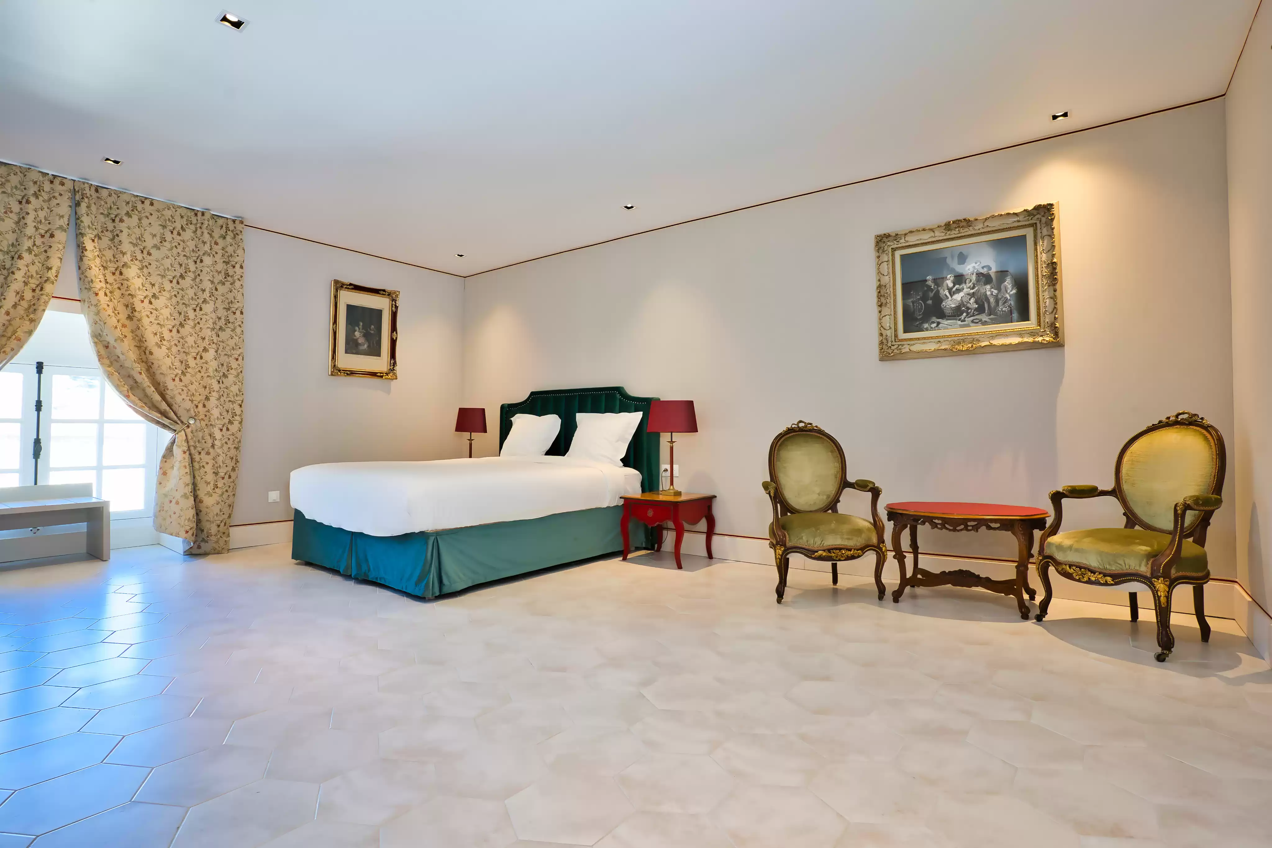 La chambre la plus spacieuse du château, lumineuse et originale, dotée d'une décoration atypique avec un lit à tête de lit en velours vert, deux fauteuils d'époque dorés et un sol en carreaux 